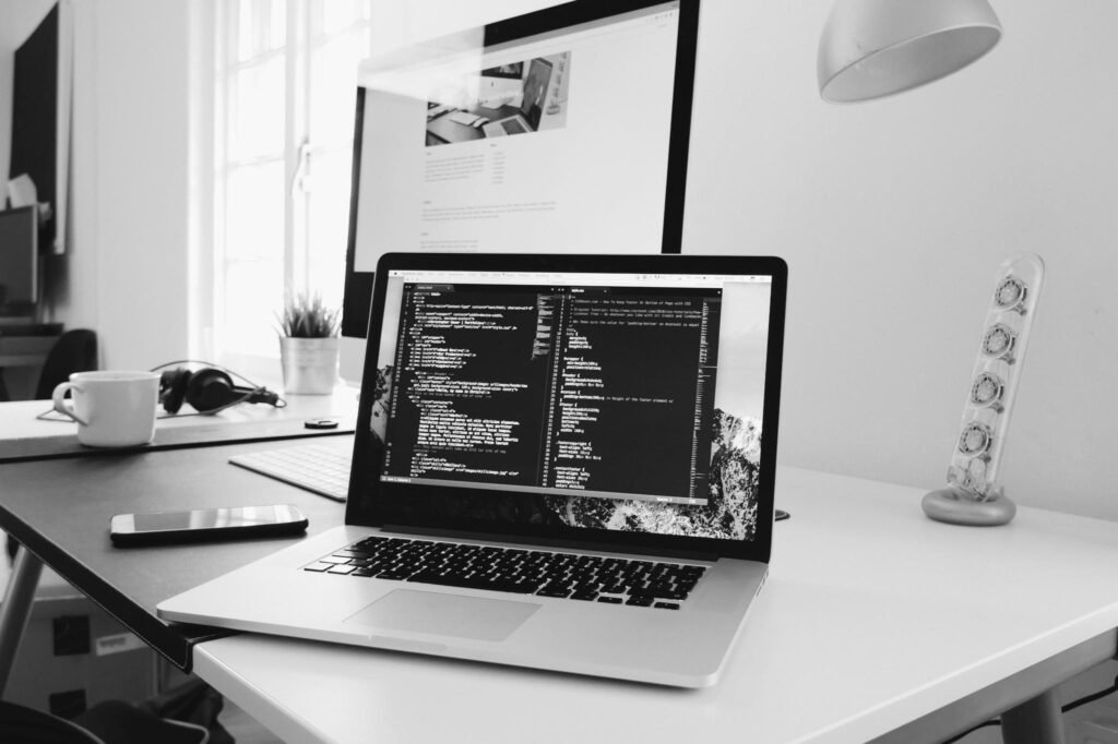 Laptop showing code on a desk in a bright office